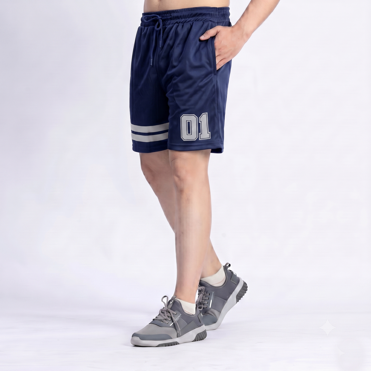 A person wearing navy blue athletic shorts with white stripes near the hem and the number 01 printed on the left leg, paired with gray sneakers, shown against a plain light background.
