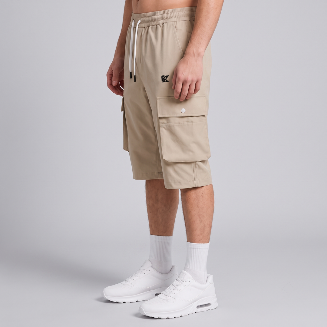 A model wearing beige cargo shorts with white drawstrings, white crew socks, and white sneakers, shown from the waist down against a light gray studio background.