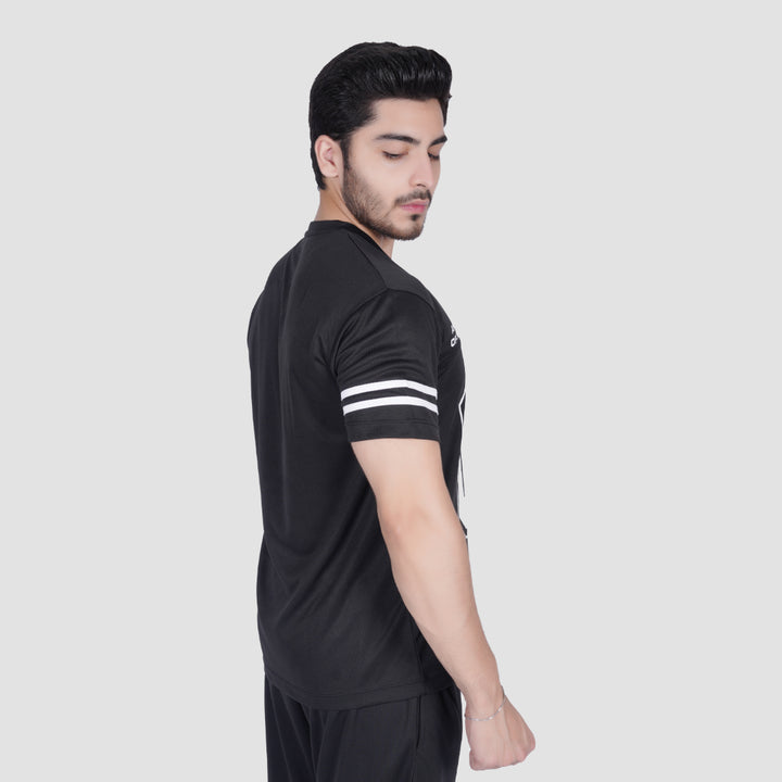 Man wearing a black sports outfit with white stripes on a light gray background