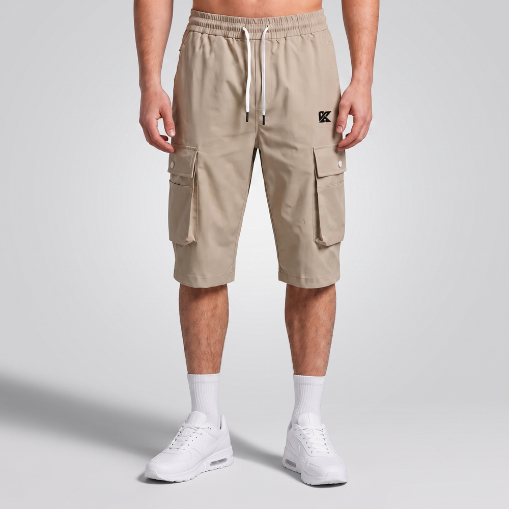 A model from the waist down wearing beige cargo shorts with a white drawstring, white crew socks, and white sneakers, standing against a light gray studio background.