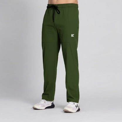 A person wearing olive green scrub pants with a black drawstring and a small white logo on the left thigh, paired with white athletic shoes, against a light gray studio background.