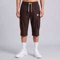 A model from the waist down wearing dark brown cargo shorts with a cream drawstring and a small white logo on the left thigh, paired with white crew socks and white sneakers, against a light gray studio background.