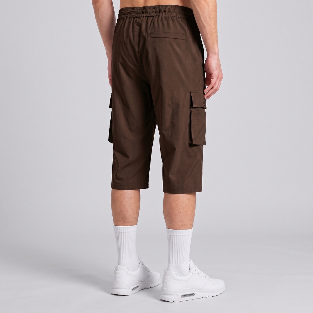 A person shown from the back wearing dark brown cargo shorts, white crew socks, and white sneakers against a light gray studio background.
