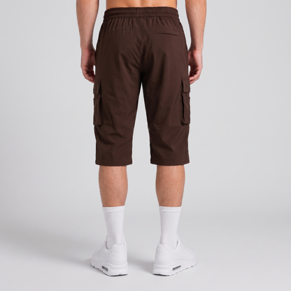 A person shown from the back wearing dark brown cargo shorts, white crew socks, and white sneakers against a light gray studio background.