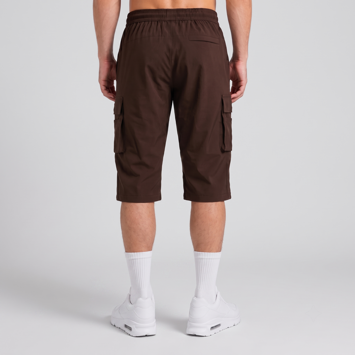 A person shown from the back wearing dark brown cargo shorts, white crew socks, and white sneakers against a light gray studio background.